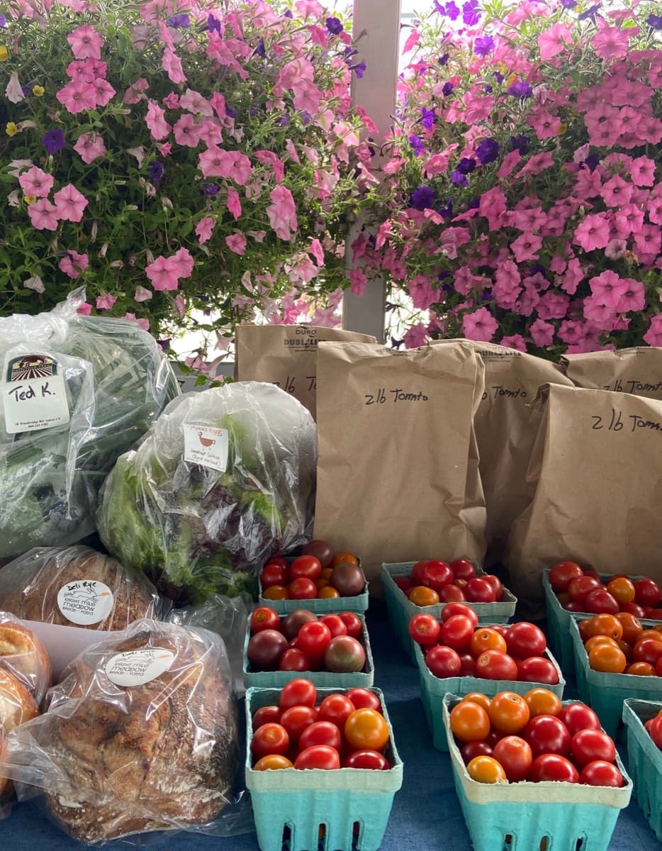 A farmers market stand stocked with fresh produce and flowers